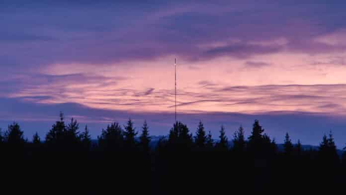 A Swedish radio tower against a purple night sky.