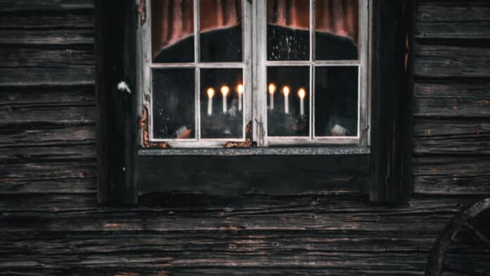 Candles in the window of a wooden cabin.
